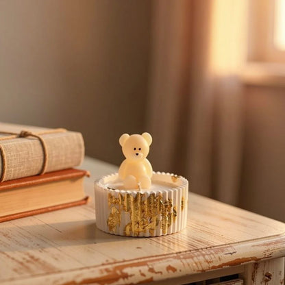 Lumânare ursuleț cu mesaj personalizat pe o masă, cu detalii aurii, ideală pentru cadou.